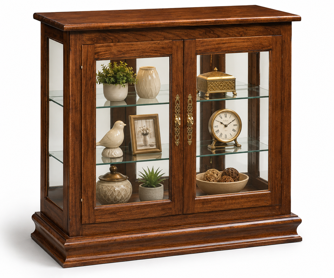 A brown wooden display cabinet with two glass doors, three glass shelves, and ornate gold handles, styled with home decor items on a white background.