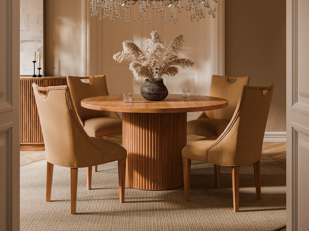 Dining room with a round wooden table and beige chairs, featuring a vase with dried plants.
