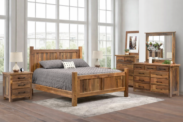 Wooden bedroom furniture set with bed, dresser, and nightstands in a room with large windows.